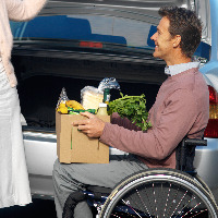 Man in a wheelchair holding groceries.
