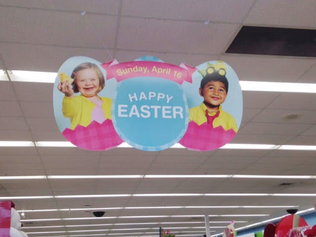 Easter display ad hanging from Walgreen's ceiling, has two children in eggs. A young girl with Down syndrome and a young boy.