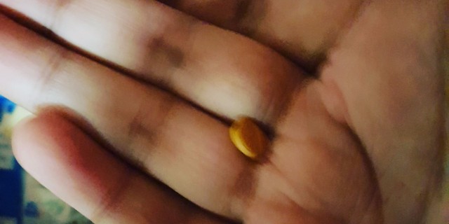 picture of a hand with a yellow pill int he middle
