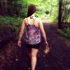 woman with a butterfly tattoo walking barefoot on a path through the woods