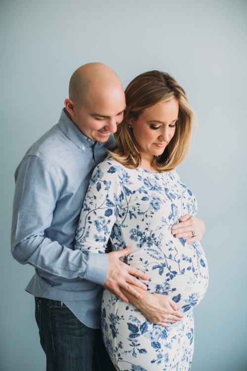 pregnant woman standing with man with hands on her stomach