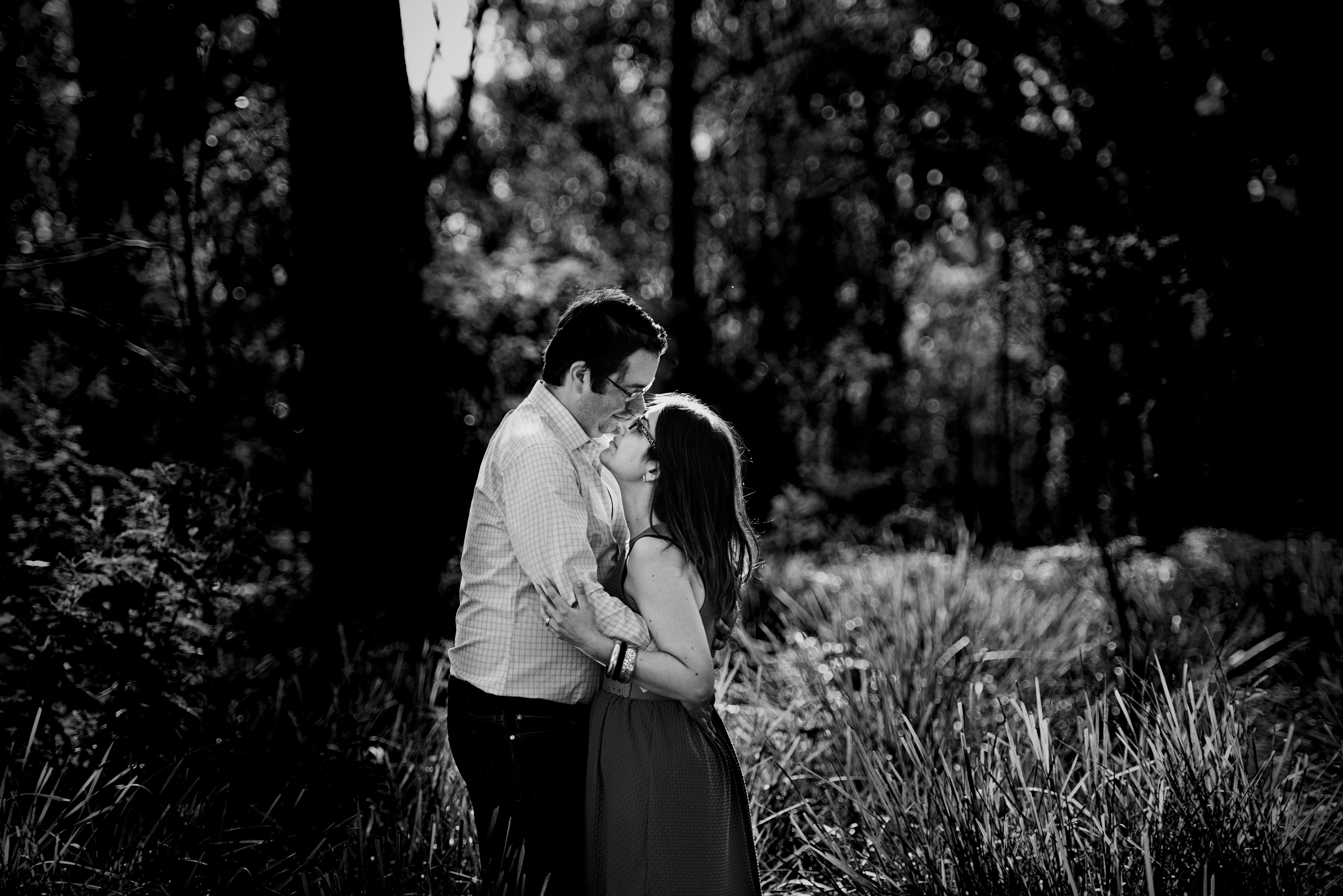 husband and wife kissing in forest