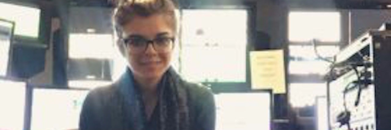 Multiple Hereditary Exostoses: Learning to Love Myself and My Scars young woman with glasses sitting cross-legged on a chair at work and smiling