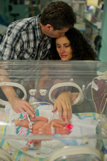 Parents with baby in incubator in hospital