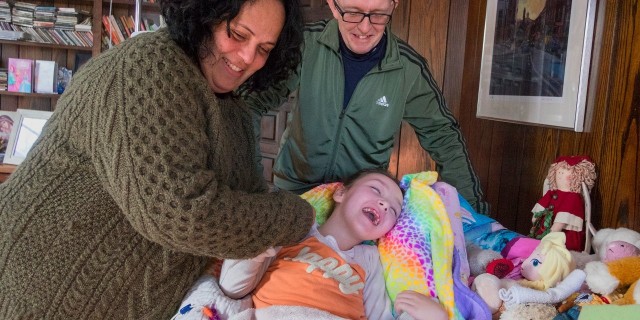 Why I'm Inviting Members of Congress to Meet My Daughter Mother and father with daughter in living room. Mother is holding daughter's hand, and all three are smiling. Photo courtesy of photographer Ed Hille