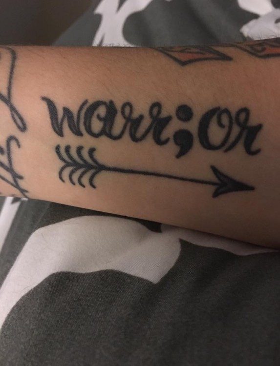 “I got the word warrior because I fight with these thoughts every day, and I survived a suicide attempt. The semicolon is in there because it symbolizes that my story isn't over. I got it right there on my arm so I can see it clearly every day and remind myself to stay strong.” — Ashley Lake