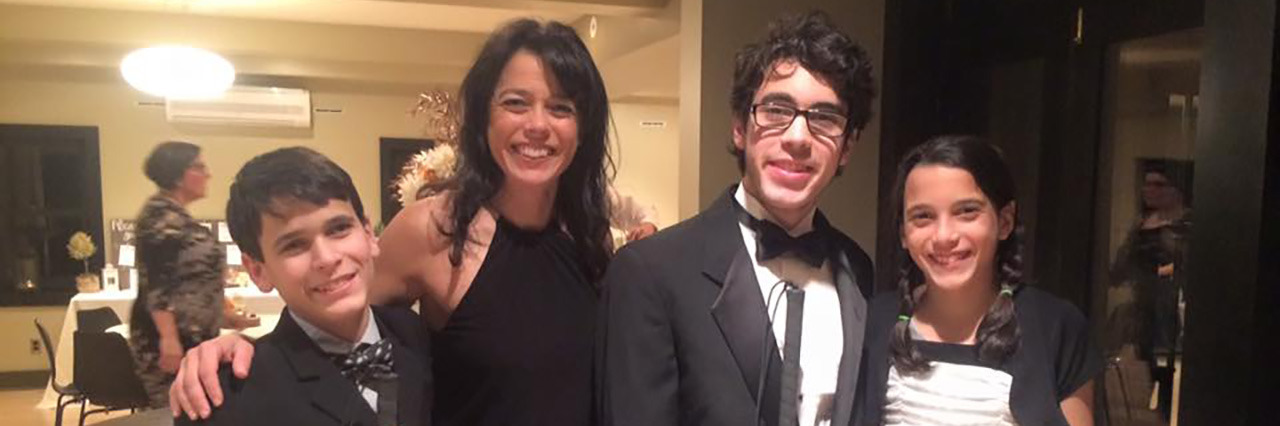 Kristin with her sons and daughter, dressed in formal attire at a party.