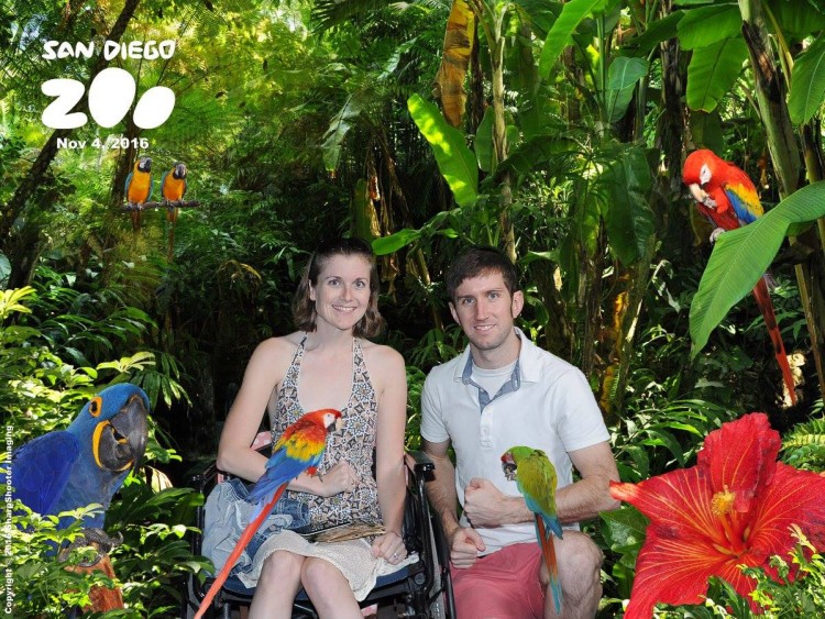 man and woman holding parrots and surrounded by palm trees