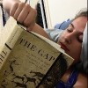 college student laying in bed and reading a book for class