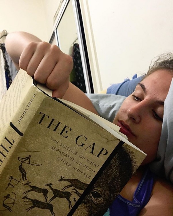 college student laying in bed and reading a book for class