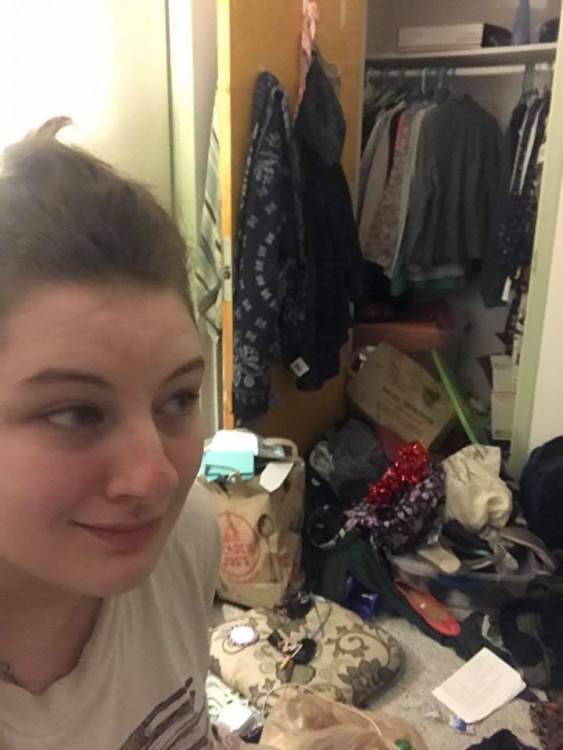 woman in dorm room with things on floor and coming out of closet