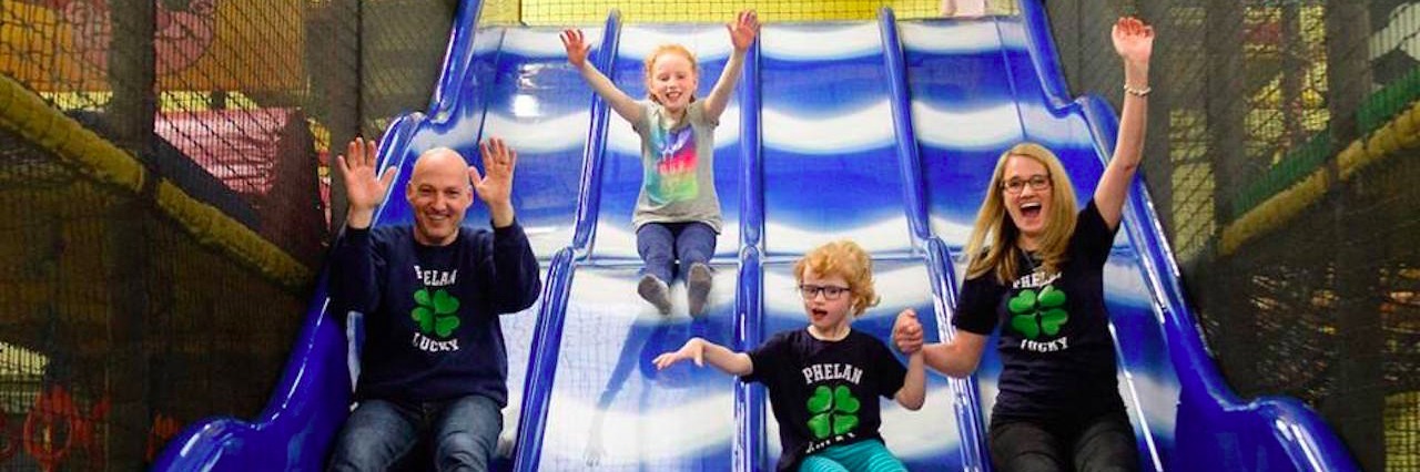 A family of four sliding down a blue slide