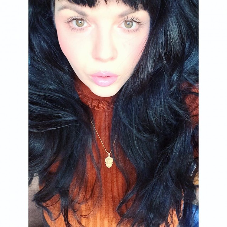 woman with long black hair and orange sweater