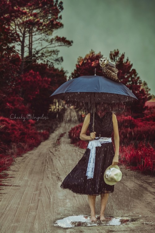 Woman without a head standing under an umbrella in the rain.