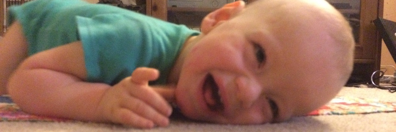 Happy baby laying on the floor on his tummy and smiling