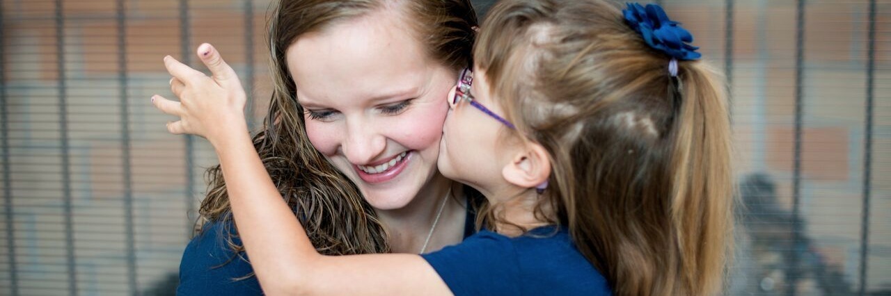 What to Know If Your Child Is Diagnosed With SATB2 Syndrome young daughter kissing her mother on the cheek