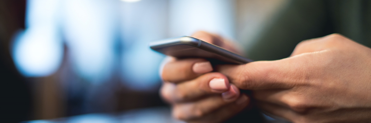 9 Tweets That Nail What Chronic Illness Can Be Like Close up of person's hands holding phone while texting.