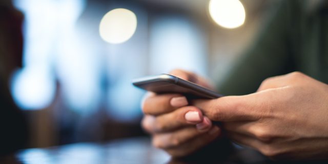 Close up of person's hands holding phone while texting.