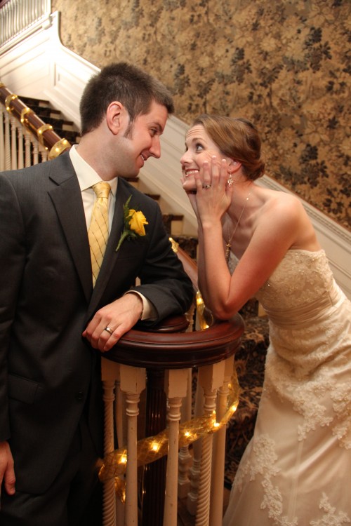 husband and wife leaning on a banister and smiling at each other