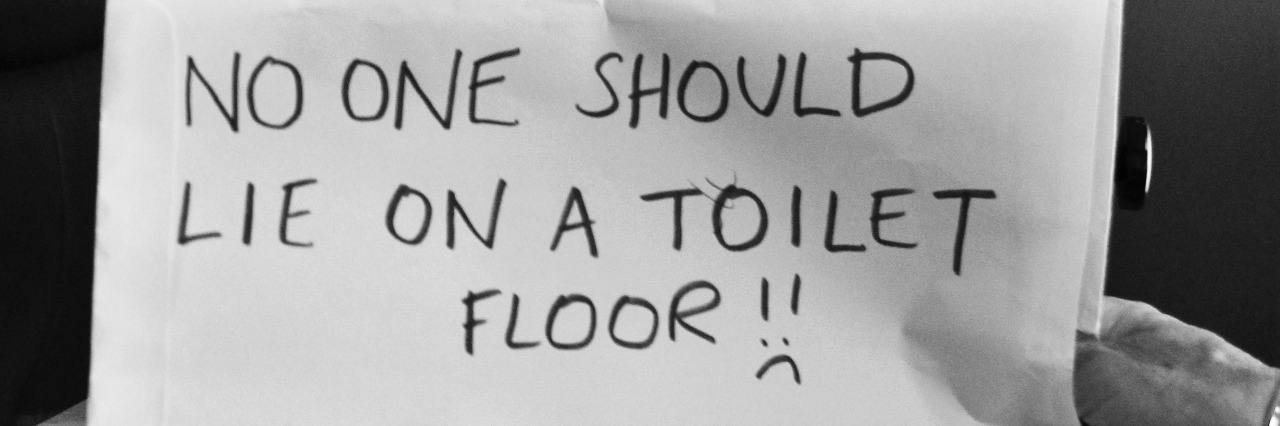Boy holding sign that reads "No one should lie on a toilet floor."