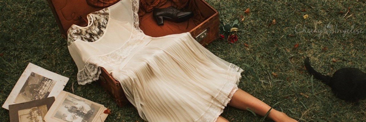 photo of a dress in a suitcase with legs sticking out