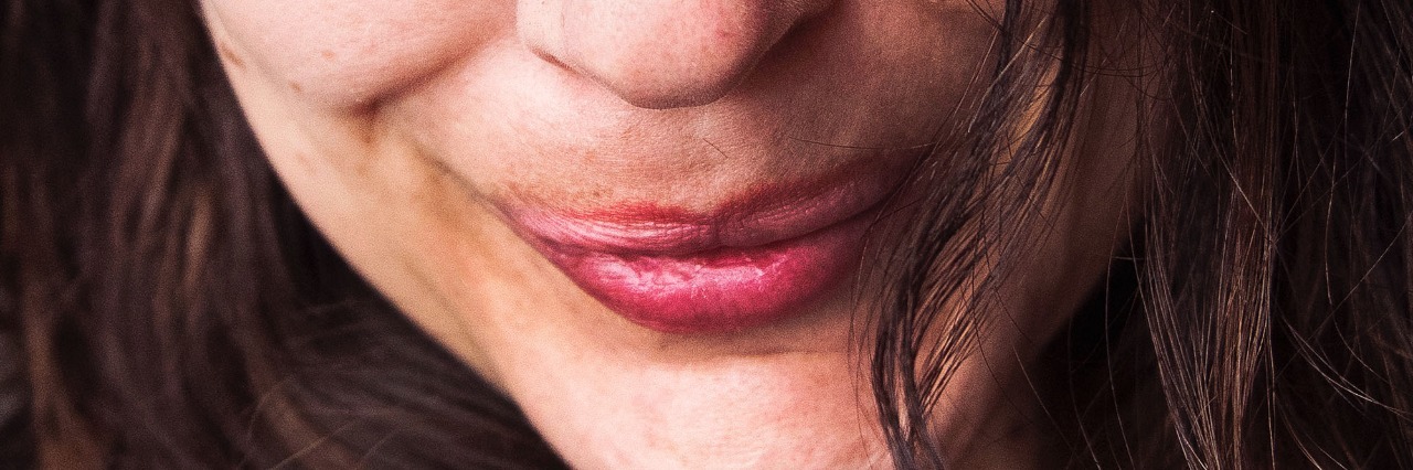 How a Single Smile From a Stranger Prevented My Suicide picture of woman with long brown hair and red lips smiling