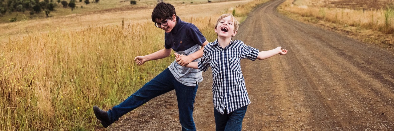 author's children laughing and smiling on road through fields
