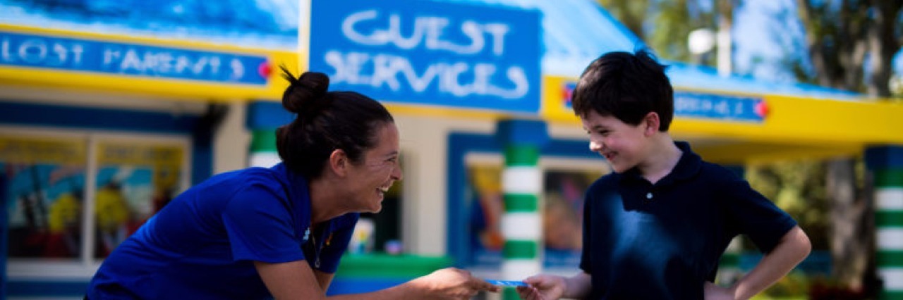 Legoland Unveils Sensory-Friendly Features for Those With Autism Legoland employee talking to a young boy.