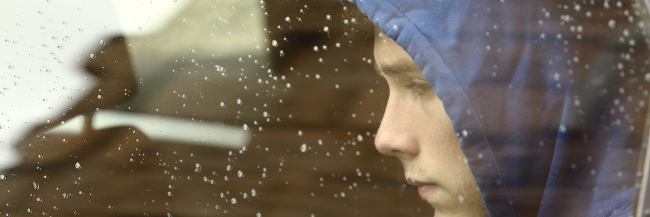 My Life With Tourette's Syndrome Confussed teenager boy wearing a blue hoodie, worried inside a car looking through the window