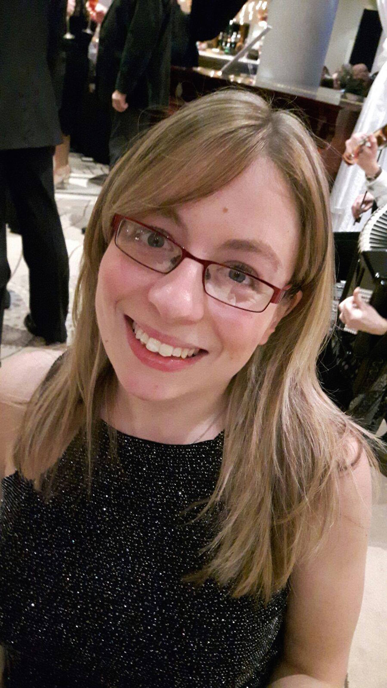 The author at a party smiling, wearing black top with silver glitter