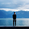 man standing in front of lake and mountains