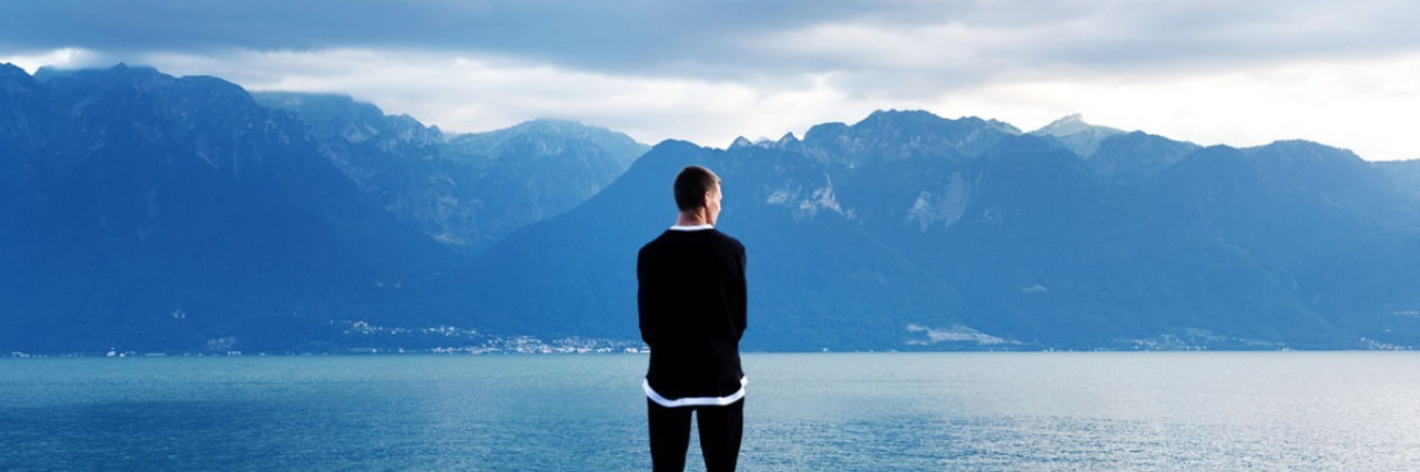 Invisible Disability Project: Dan Peterson man standing in front of lake and mountains