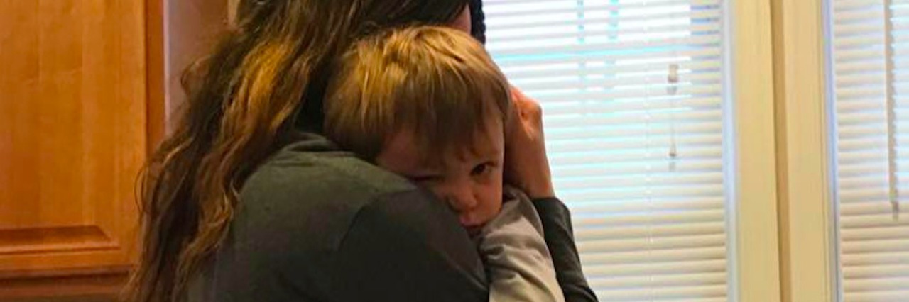 A Letter of Love to My Son With Hydrocephalus Mom holding baby son while standing in kitchen near sink