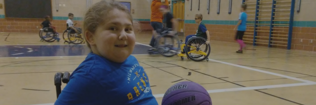 little girl in wheelchair playing basketball