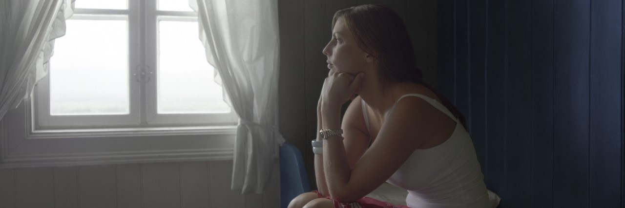 Sad Woman Sitting Alone in Room, daydreaming, side view