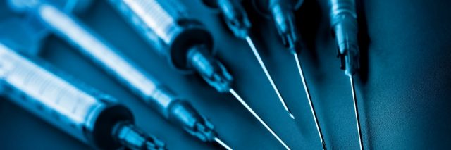 Closeup of syringes on black background. Toned image. Selective focus on the needle tips. For medical and laboratory themes