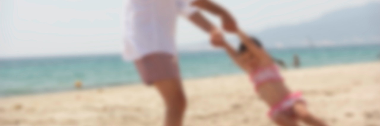 How My Father's Suicide Forced Me To Acknowledge My Own Mental Illness A man swinging his daughter on the beach