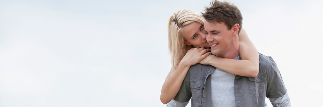 Thank You Letter to Boyfriend For Support Through Chronic Illness man walking on a grassy beach and giving a woman a piggyback ride