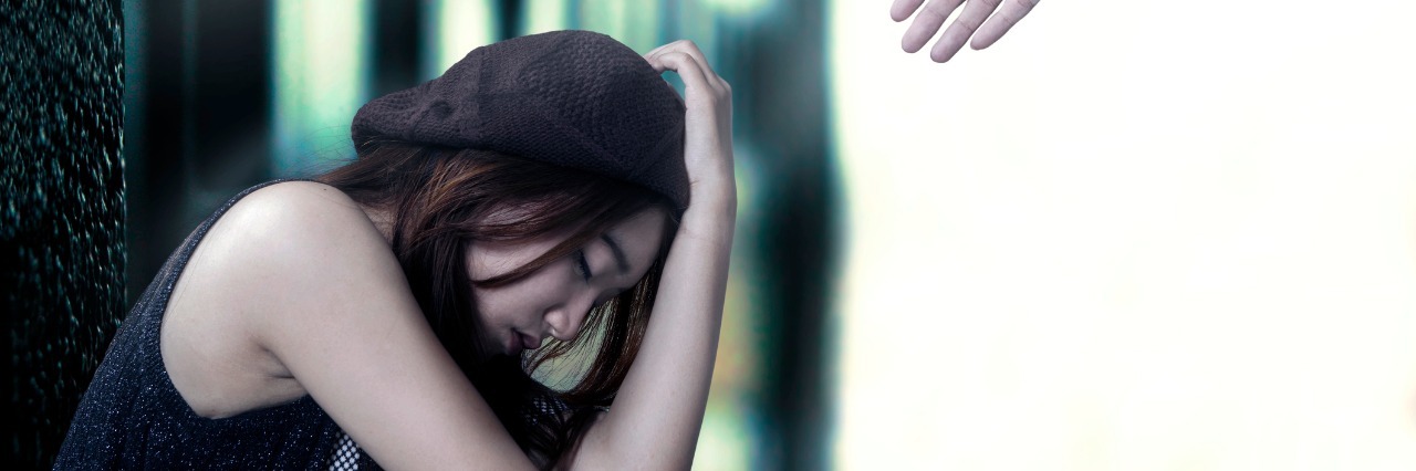 5 Lessons Chronic Pain Has Taught Me Portrait of stressful teenage girl sitting on the floor with a hand coming out from bright background offers help