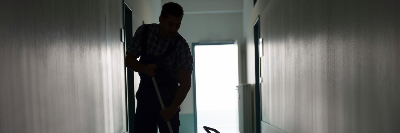 Full length of silhouette man with broom cleaning office corridor
