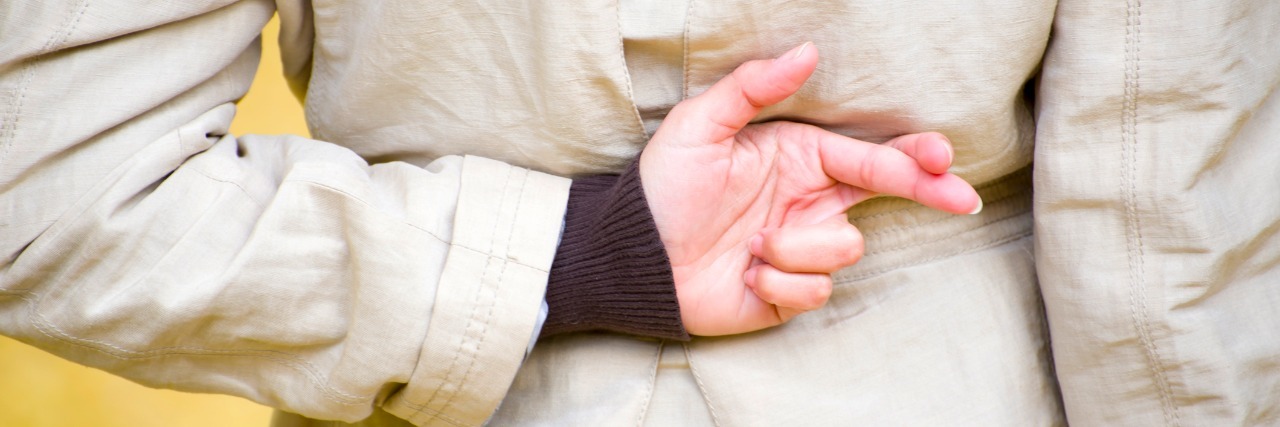 'How am I? Fine' (and Other Lies I Tell Because of My Health) Woman crossing fingers behind her back