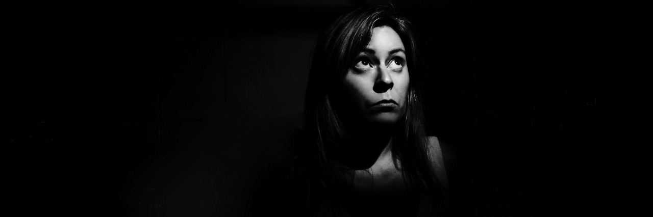 A woman in the dark looking up into a shaft of light