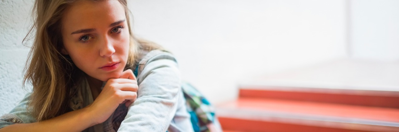 What a 'Rough Day' Means for a College Student with Lyme Disease Sad lonely student sitting on stairs looking at camera