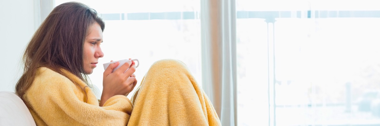 3 Types of Days I Have With Ehlers-Danlos Syndrome Side view of sick woman having coffee on sofa in living room