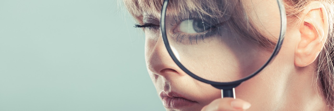 What It's Like to Have Severe Myalgic Encephalomyelitis (ME) woman looking through magnifying lens with her eye appearing large