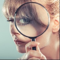 woman looking through magnifying lens with her eye appearing large