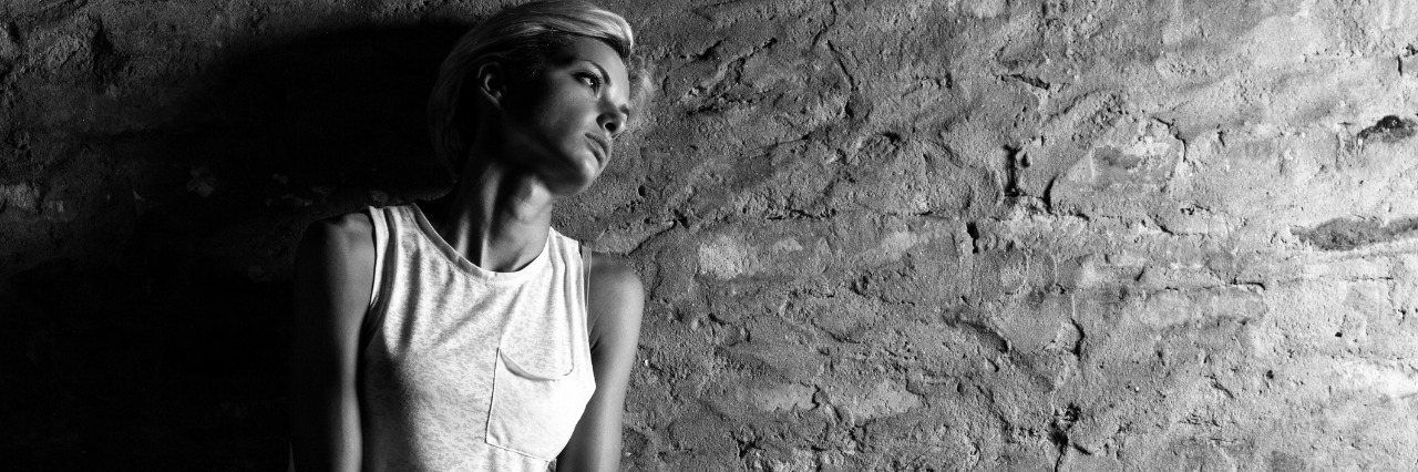 Please Don't Tell Me How To Feel When My Pain Flares-Up Lonely young woman sitting on the street, looking severely depressed. Black and white.