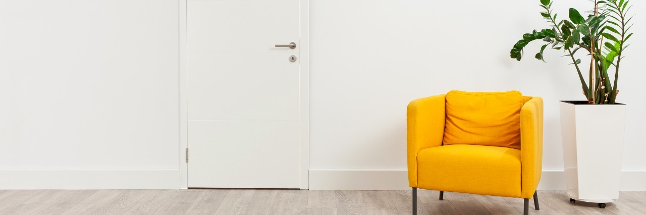 How to Approach Therapy Sessions with Transgender Clients Contemporary waiting room with a yellow armchair and a plant in a white flowerpot behind it