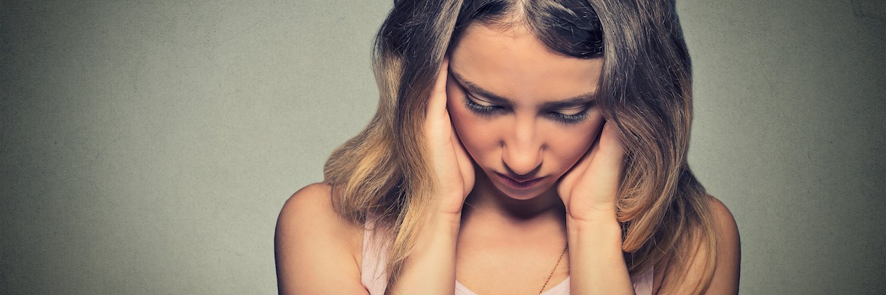 Depression and What It Means to Feel Exhausted Constantly A woman with her head down