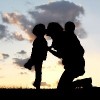 silhouette of mother and two children in a field during sunset